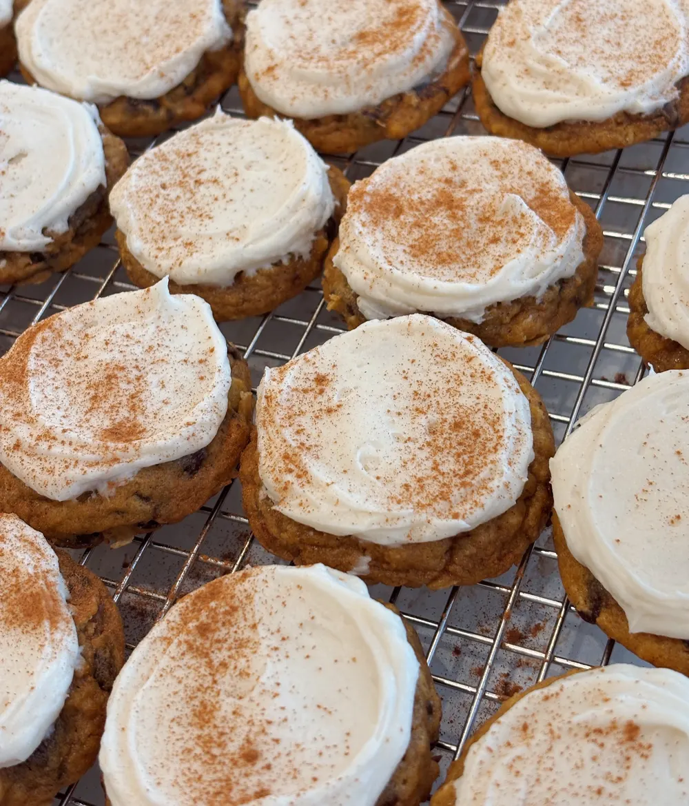Frosted pumpkin cookies cooling on a rack